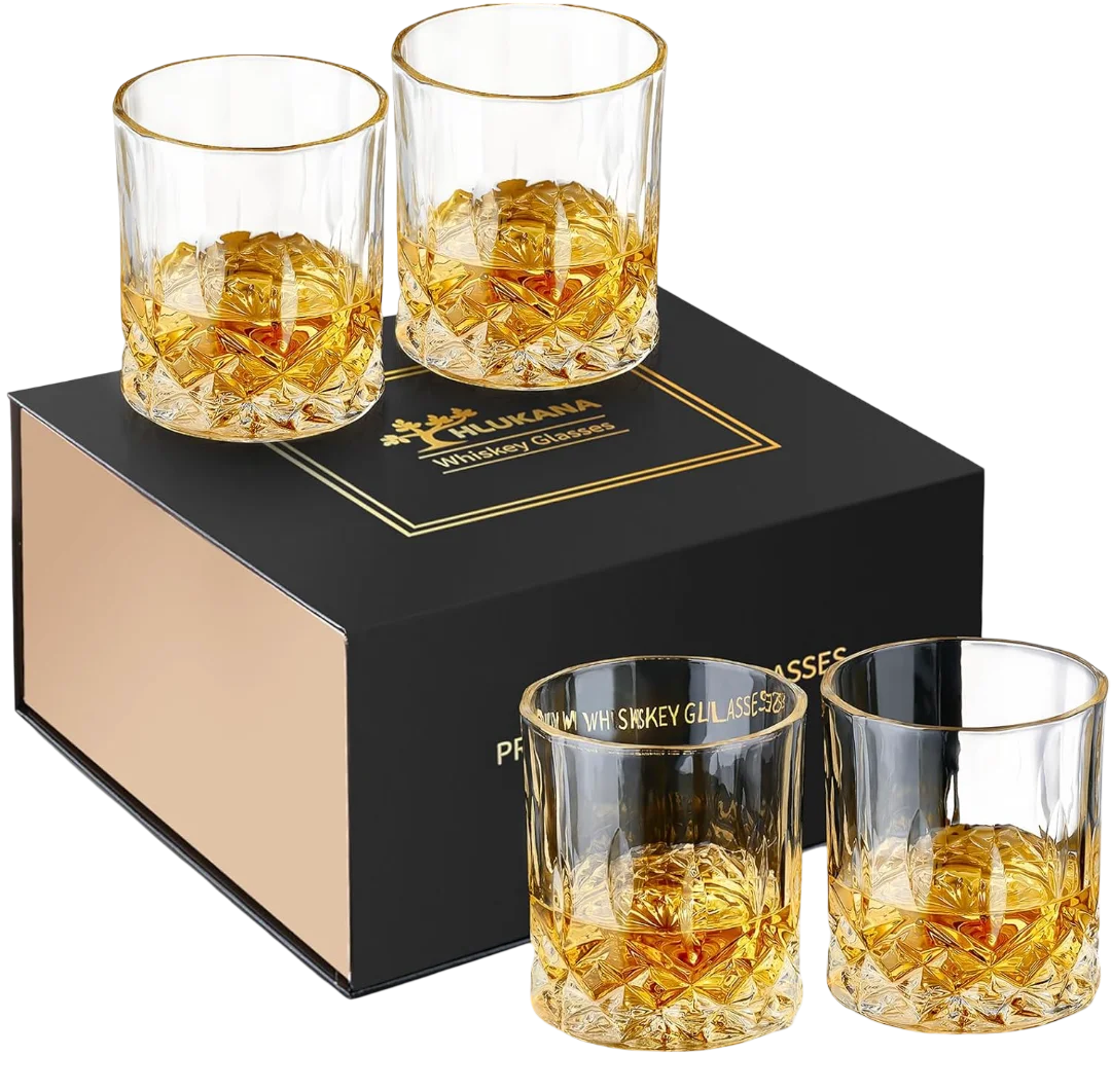 Four premium glass whiskey tumblers with diamond-cut pattern, filled with amber whiskey and ice balls, arranged around a black and gold Hlukana gift box